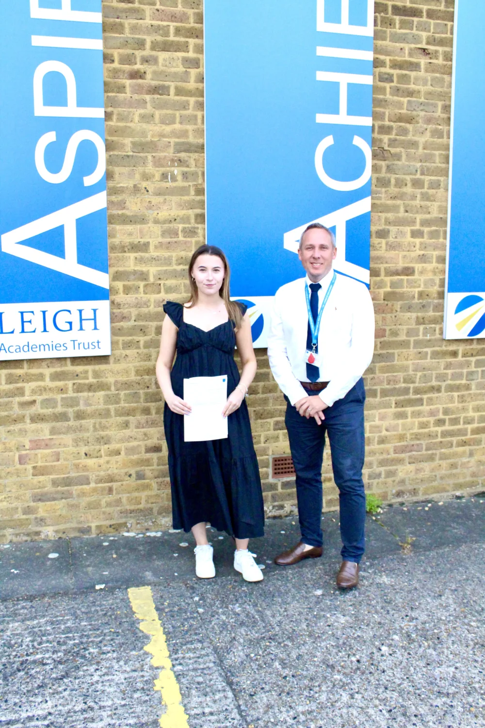 Student holding their results with a staff member