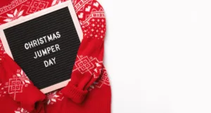 Red Christmas sweater and letter board with words Christmas jumper day.