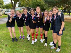 A group of girls in rugby kits smiling for a photo